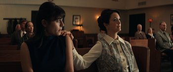 Movie still from “Jesus Revolution” (2023), directed by Brent McCorkle – Two women are sitting in a room and one of them has her hand on the other's shoulder; Medium shot, Low angle