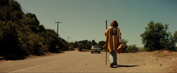 Movie still from “Jesus Revolution” (2023), directed by Brent McCorkle – A man walking down a road with a stick; Wide shot, Low angle
