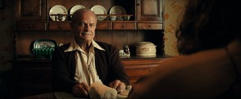 Movie still from “Jesus Revolution” (2023), directed by Brent McCorkle – An older man sitting in front of a wooden cabinet; Medium shot, Over the shoulder angle