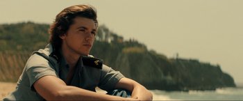 Movie still from “Jesus Revolution” (2023), directed by Brent McCorkle – A man in a uniform sitting on the side of a boat; Medium shot, Low angle