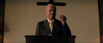 Movie still from “Jesus Revolution” (2023), directed by Brent McCorkle – An older man in a suit and tie holding a cigarette; Close Up shot, Low angle