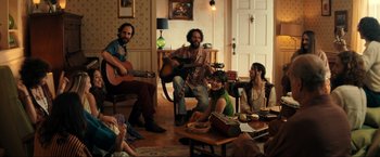 Movie still from “Jesus Revolution” (2023), directed by Brent McCorkle – A group of people sitting around a living room; Wide shot, High angle