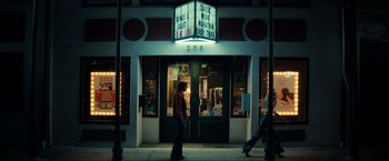 Movie still from “Jesus Revolution” (2023), directed by Brent McCorkle – A person walking in front of a movie theater; Wide shot, Low angle