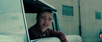 Movie still from “Jesus Revolution” (2023), directed by Brent McCorkle – A young man sitting in the back seat of a car crying; Close Up shot, High angle