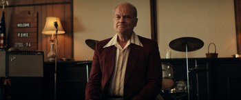 Movie still from “Jesus Revolution” (2023), directed by Brent McCorkle – An older man wearing a brown jacket and a white shirt; Medium shot, Low angle