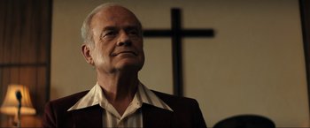 Movie still from “Jesus Revolution” (2023), directed by Brent McCorkle – An older man standing in front of a wooden cross; Close Up shot, Low angle