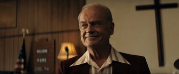 Movie still from “Jesus Revolution” (2023), directed by Brent McCorkle – An older man wearing a red jacket and a white shirt; Close Up shot, Over the shoulder angle