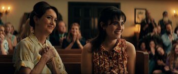 Movie still from “Jesus Revolution” (2023), directed by Brent McCorkle – Two women sitting in front of other people in a room; Close Up shot, Over the shoulder angle