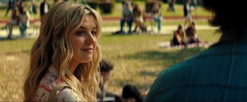 Movie still from “Jesus Revolution” (2023), directed by Brent McCorkle – A beautiful young lady sitting in the grass; Close Up shot, Over the shoulder angle