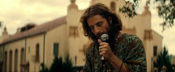 Movie still from “Jesus Revolution” (2023), directed by Brent McCorkle – A man with long hair is holding a microphone; Close Up shot, Low angle