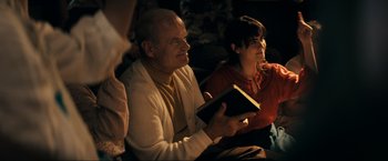Movie still from “Jesus Revolution” (2023), directed by Brent McCorkle – A man and a woman sitting next to each other holding a book; Medium shot, Over the shoulder angle