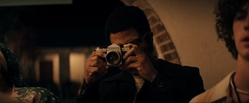 Movie still from “Jesus Revolution” (2023), directed by Brent McCorkle – A man taking a picture with a camera; Close Up shot, Low angle