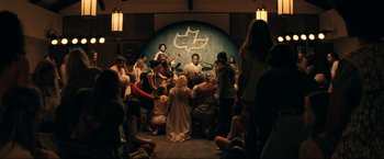 Movie still from “Jesus Revolution” (2023), directed by Brent McCorkle – A group of people gathered in a room; Wide shot, High angle