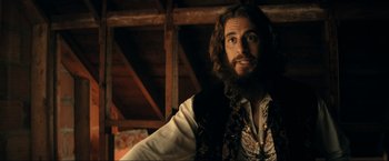 Movie still from “Jesus Revolution” (2023), directed by Brent McCorkle – A man with long hair and a beard wearing a vest; Close Up shot, Over the shoulder angle