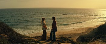 Movie still from “Jesus Revolution” (2023), directed by Brent McCorkle – Two people standing on the beach near the ocean; Wide shot, High angle