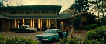 Movie still from “Jesus Revolution” (2023), directed by Brent McCorkle – Two people standing in front of an old blue car; Extreme Wide shot, Low angle