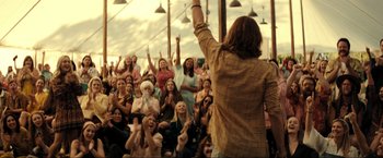 Movie still from “Jesus Revolution” (2023), directed by Brent McCorkle – A group of people sitting in front of an audience; Wide shot, Over the shoulder angle