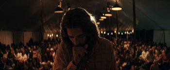 Movie still from “Jesus Revolution” (2023), directed by Brent McCorkle – A man with long brown hair standing in front of a crowd; Medium shot, Low angle
