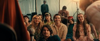 Movie still from “Jesus Revolution” (2023), directed by Brent McCorkle – A group of young people sitting in front of an audience; Medium shot, Over the shoulder angle