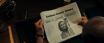 Movie still from “Jesus Revolution” (2023), directed by Brent McCorkle – A person holding a newspaper with a picture of a man; Close Up shot, High angle