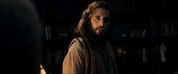 Movie still from “Jesus Revolution” (2023), directed by Brent McCorkle – A man with long hair and a beard is standing; Medium shot, Over the shoulder angle