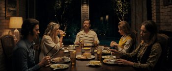 Movie still from “Jesus Revolution” (2023), directed by Brent McCorkle – A group of people sitting at a dinner table eating food; Wide shot, Over the shoulder angle