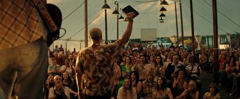 Movie still from “Jesus Revolution” (2023), directed by Brent McCorkle – A man holding a bible in front of a crowd of people; Wide shot, Low angle