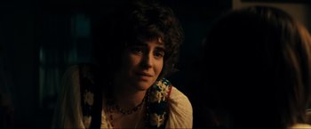 Movie still from “Jesus Revolution” (2023), directed by Brent McCorkle – A young woman with curly brown hair wearing a necklace; Close Up shot, Over the shoulder angle