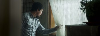 Movie still from “Joe Bell” (2020), directed by Reinaldo Marcus Green – A man standing in front of a window looking out at the outside; Medium shot, Low angle