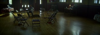 Movie still from “Joe Bell” (2020), directed by Reinaldo Marcus Green – A group of folding chairs in a room; Extreme Wide shot, High angle