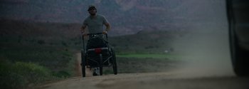Movie still from “Joe Bell” (2020), directed by Reinaldo Marcus Green – A man is pulling a cart down a dirt road; Wide shot, Low angle