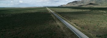 Movie still from “Joe Bell” (2020), directed by Reinaldo Marcus Green – An aerial view of an empty road in the middle of a field; Extreme Wide shot, High angle