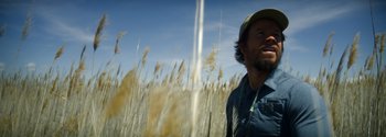 Movie still from “Joe Bell” (2020), directed by Reinaldo Marcus Green – A man standing in a field of tall grass; Close Up shot, Low angle