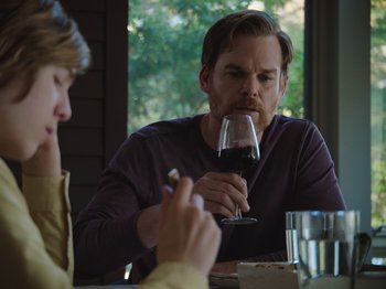 Movie still from “John and the Hole” (2021), directed by Pascual Sisto – A man sitting at a table drinking a glass of wine; Medium shot, Over the shoulder angle