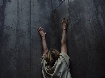 Movie still from “John and the Hole” (2021), directed by Pascual Sisto – A person reaching up into the air on a wall; Medium shot, Overhead angle