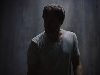 Movie still from “John and the Hole” (2021), directed by Pascual Sisto – A man in a white t - shirt standing in front of a wall; Medium shot, Low angle