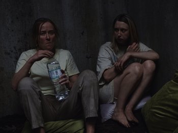 Movie still from “John and the Hole” (2021), directed by Pascual Sisto – A couple of people that are sitting on the ground; Medium shot, High angle