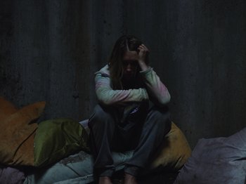 Movie still from “John and the Hole” (2021), directed by Pascual Sisto – A woman sitting on a bed with her head in her hands; Medium shot, High angle