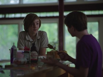 Movie still from “John and the Hole” (2021), directed by Pascual Sisto – Two people sitting at a table eating food; Medium shot, Over the shoulder angle