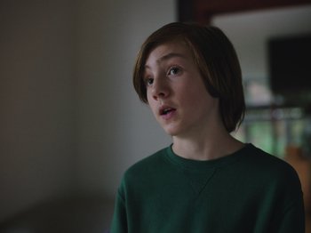 Movie still from “John and the Hole” (2021), directed by Pascual Sisto – A young person with short brown hair wearing a green shirt; Close Up shot, Low angle