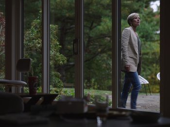 Movie still from “John and the Hole” (2021), directed by Pascual Sisto – A woman standing in front of a sliding glass door; Wide shot, Low angle