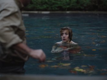 Movie still from “John and the Hole” (2021), directed by Pascual Sisto – A boy in the water with his mouth wide open; Medium shot, Over the shoulder angle