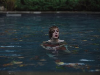 Movie still from “John and the Hole” (2021), directed by Pascual Sisto – A person in a pool of water surrounded by leaves; Close Up shot, High angle