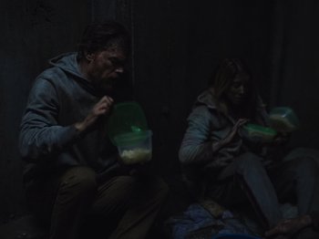 Movie still from “John and the Hole” (2021), directed by Pascual Sisto – A man and a woman sitting on the ground eating food; Medium shot, High angle