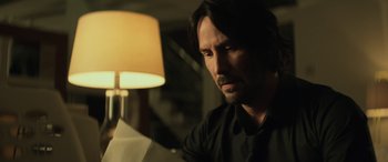 Movie still from “John Wick” (2014), directed by Chad Stahelski – A man sitting in front of a table lamp; Close Up shot, Low angle
