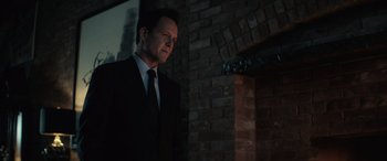 Movie still from “John Wick” (2014), directed by Chad Stahelski – A man wearing a suit and tie standing in front of a brick wall; Close Up shot, Over the shoulder angle