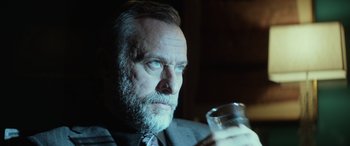 Movie still from “John Wick” (2014), directed by Chad Stahelski – An older man with a beard and a glass of wine; Close Up shot, Low angle