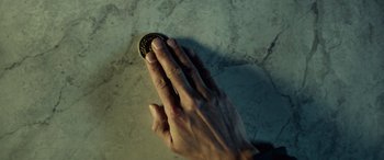 Movie still from “John Wick” (2014), directed by Chad Stahelski – A hand is touching a coin on a marble surface; Extreme Close Up shot, Overhead angle