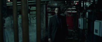 Movie still from “John Wick” (2014), directed by Chad Stahelski – A man in a suit and tie standing in a room; Medium shot, Low angle