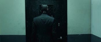 Movie still from “John Wick” (2014), directed by Chad Stahelski – A man standing in front of an open door; Medium shot, Low angle